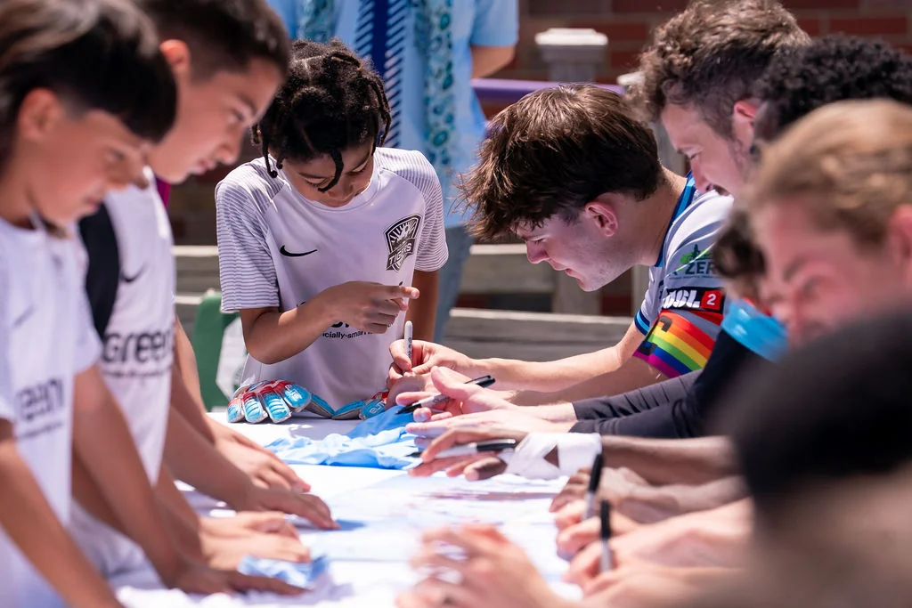 Young fans and AFC Ann Arbor players gathered along the autograph table, signing posters and soccer gear.